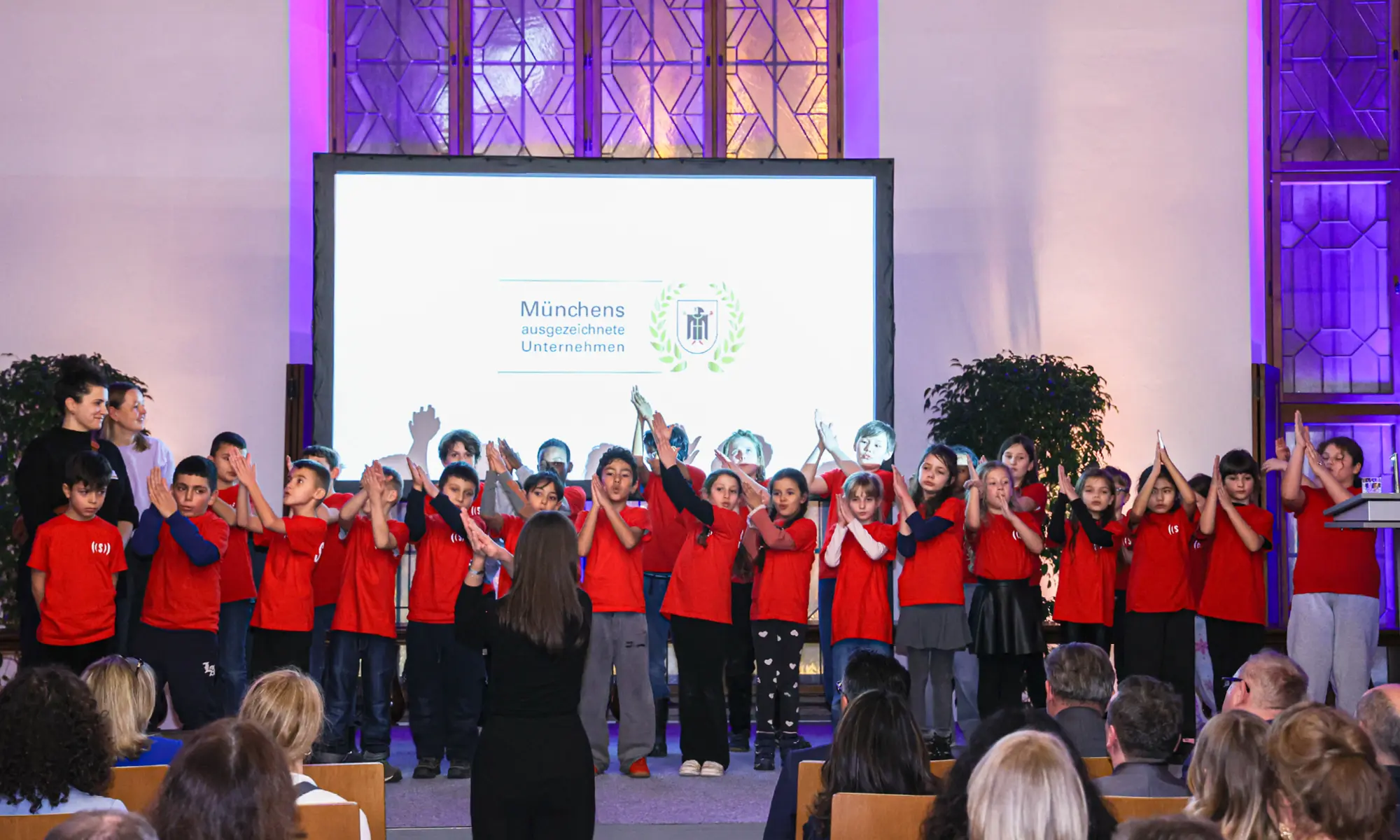 Die Kinder des Superar Chors stehen auf der Bühne und bewegen ihre Hände zur Musik.