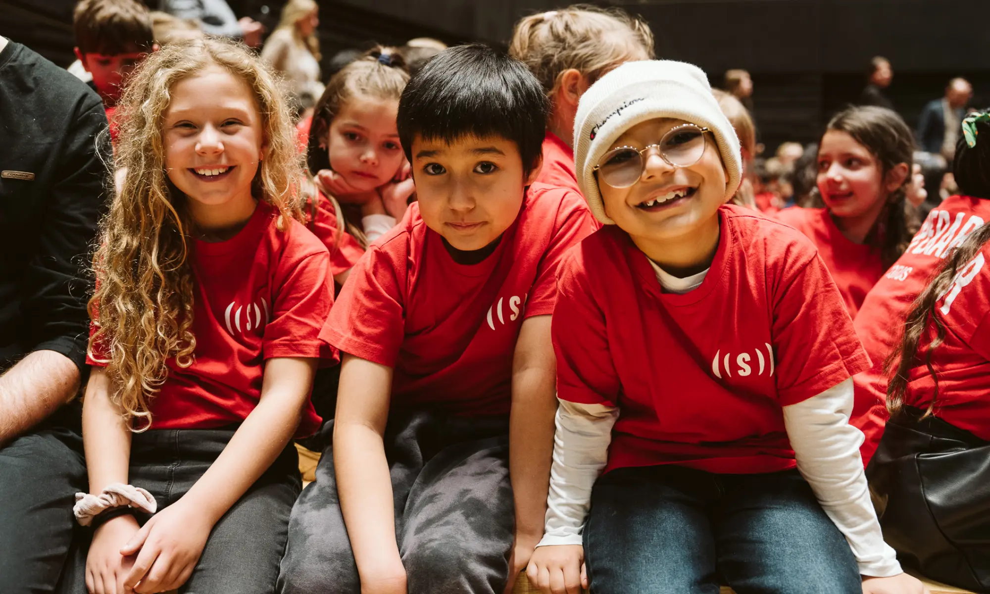 Drei Kinder lachen in die Kamera beim Superar Jahreskonzert 2025